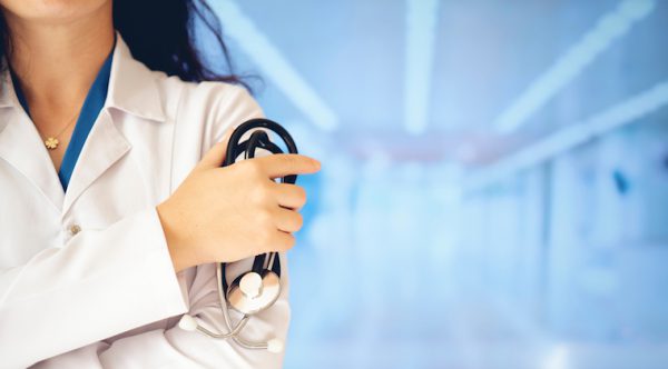 Female doctor holding a stethoscope to her arm.