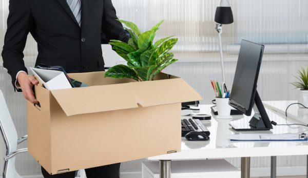 Person at a desk holding a box of items.