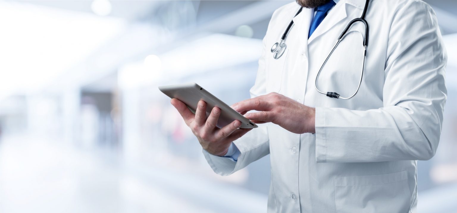 A doctor holding and using a tablet.