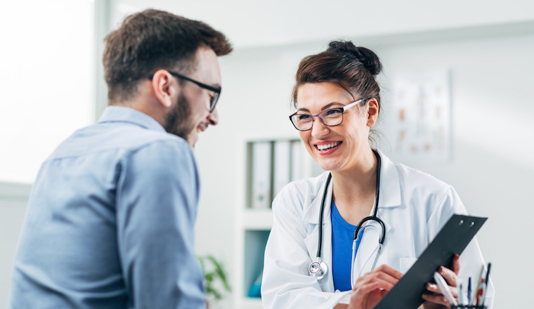 A medical consultant looking over a document with someone while smiling.