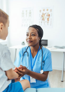 A doctor is holding the hand of a young boy in a hospital