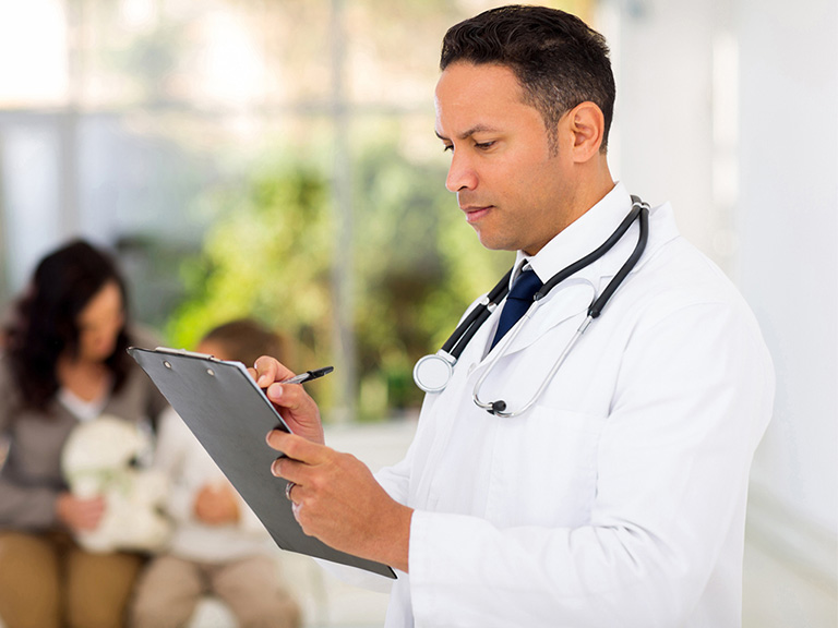 Doctor holding a clipboard, writing notes.