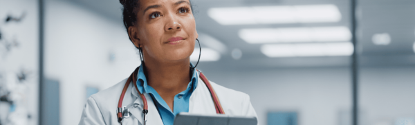 Doctor holding a tablet, looking off into the distance