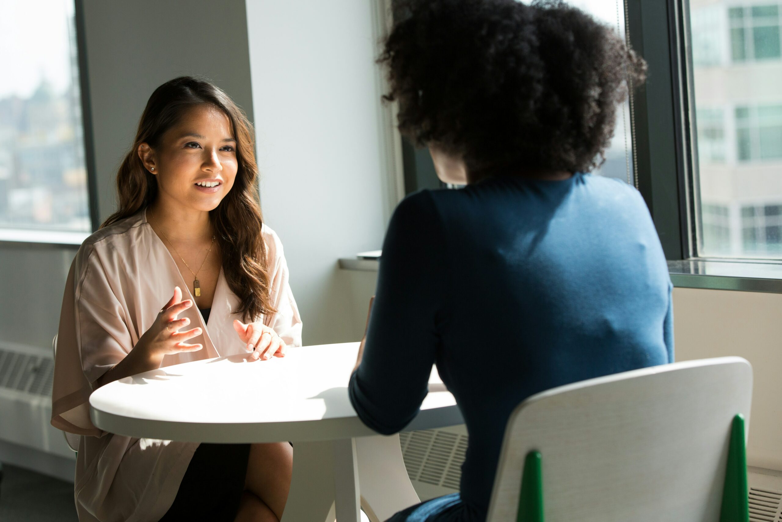 two women are sitting at a table having a conversation