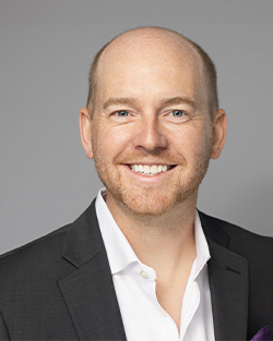 a man in a suit and white shirt smiles for the camera