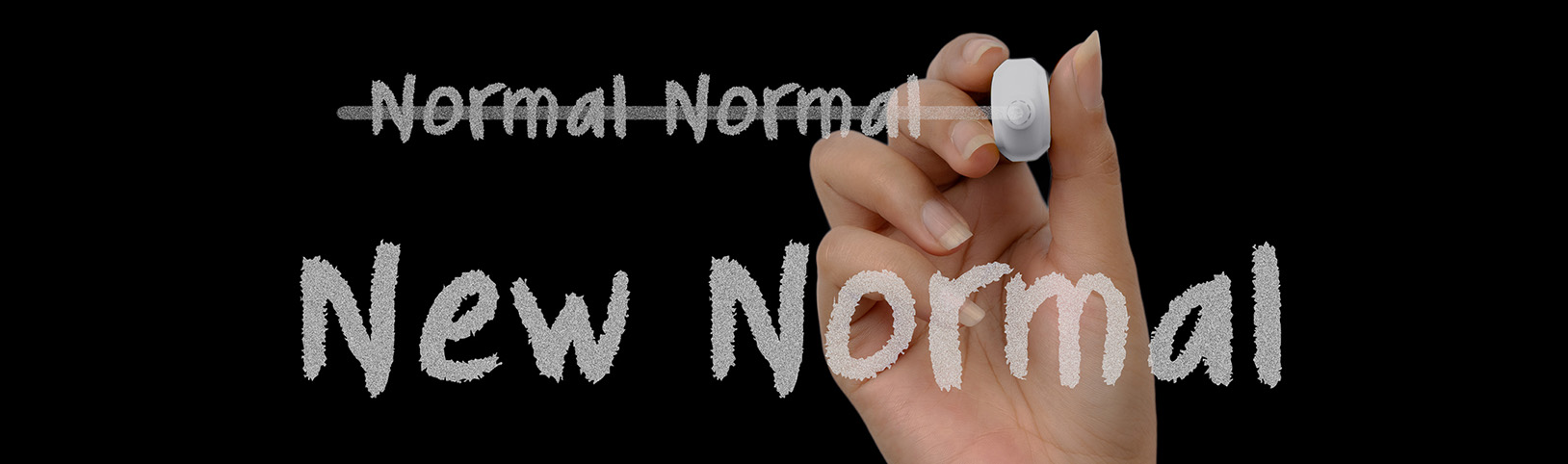 A hand with chalk crossing off "Normal Normal" with "New Normal" written in chalk below it.