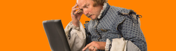 Man dressed in historical clothing looking confused on a laptop.