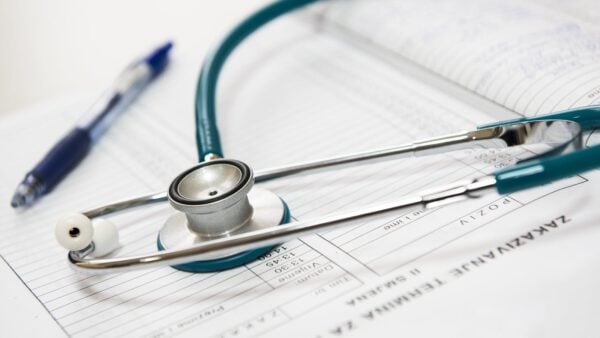 Stethoscope and pen resting on a medical report representing healthcare regulatory compliance