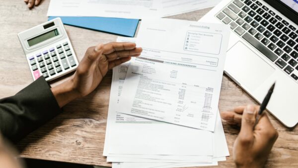 Healthcare practice owner planning a startup budget with calculator, financial documents, and laptop on a desk