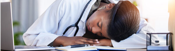 a doctor with a stethoscope around her neck is sleeping at her desk