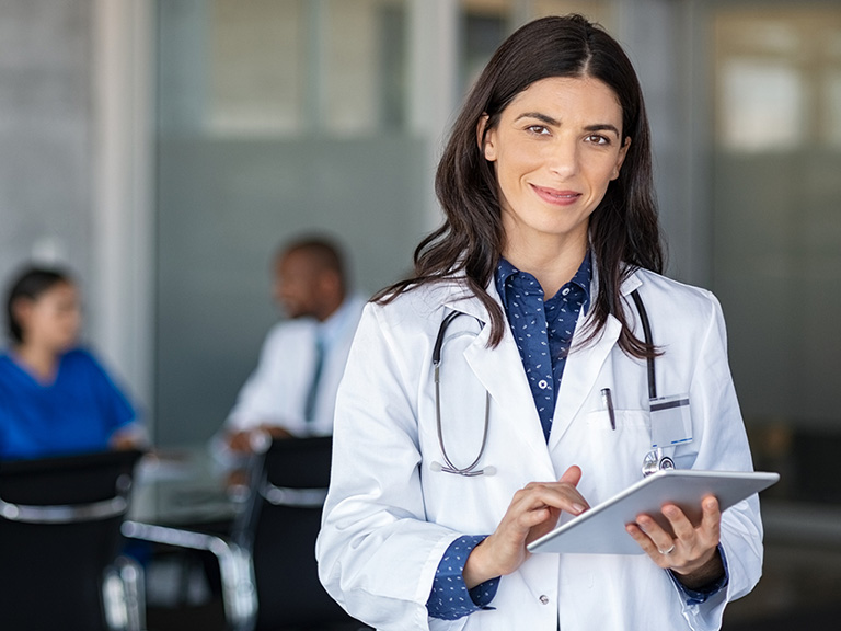 a female doctor is smiling while holding a tablet