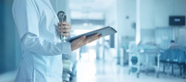 Medicine doctor with tablet and stethoscope in hand and patient waiting for examination in hospital background.