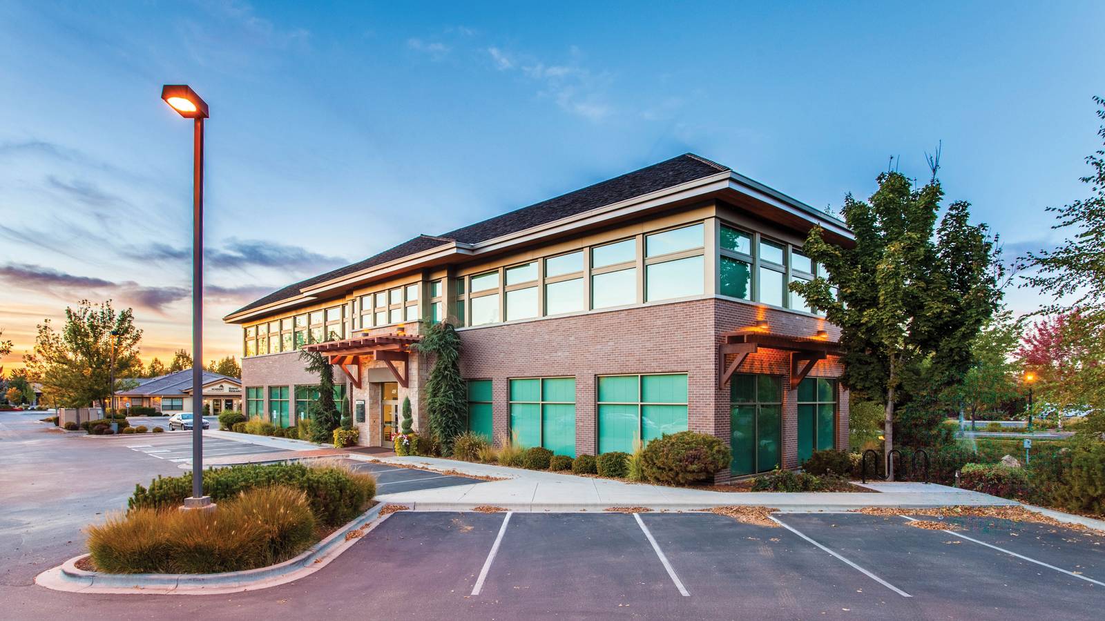 A freestanding two-story medical office building with its own parking lot at sunset, representing a practice that owns the building it occupies