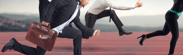 Businesspeople running on a track in suits.