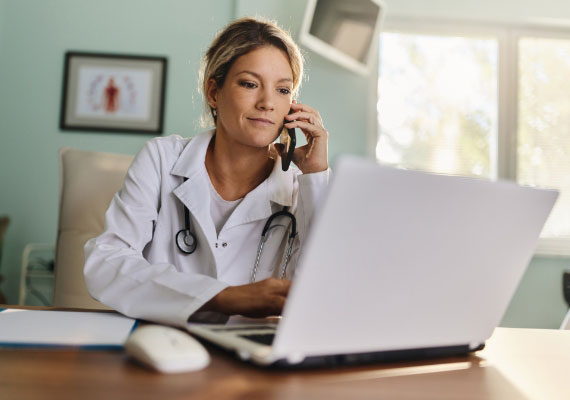 a doctor is talking on a cell phone while using a laptop