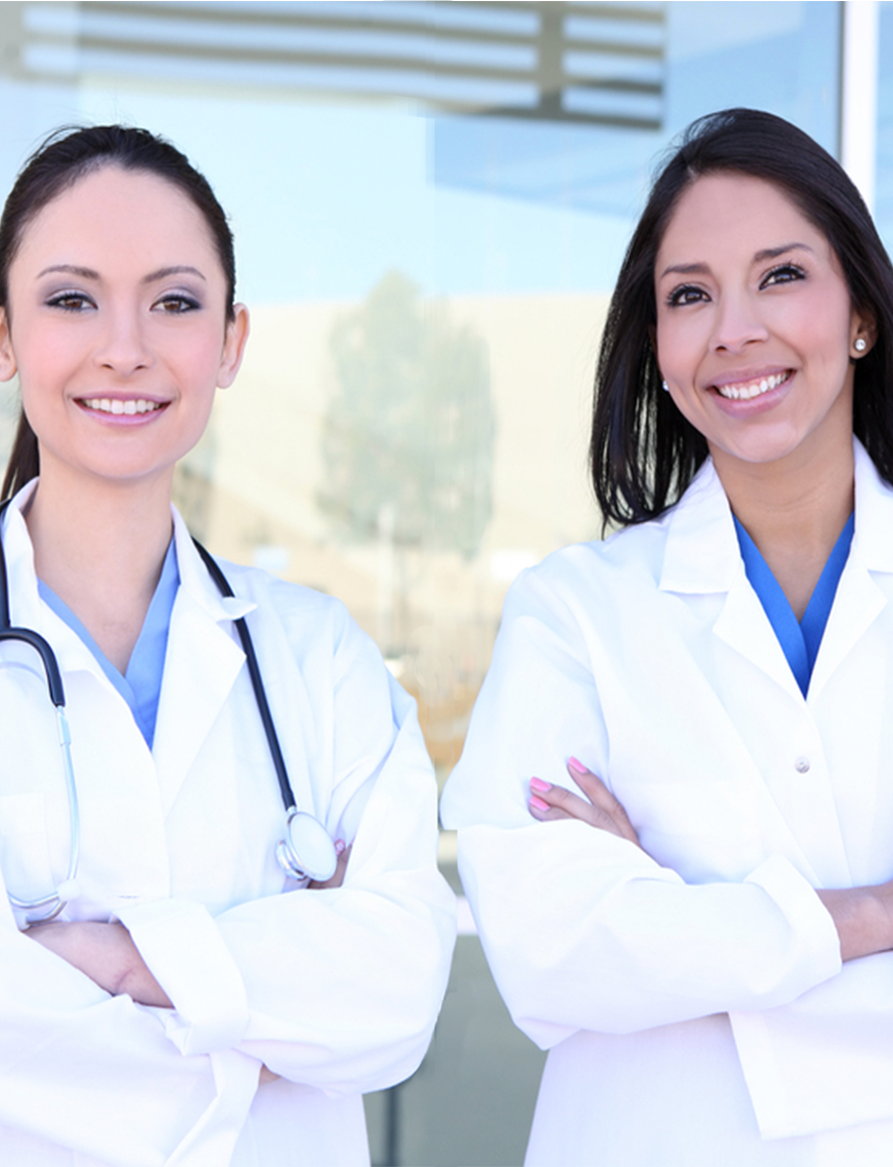 Two female doctors smiling with their arms crossed.